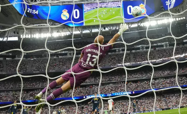 Espanyol's goalkeeper Marko Dmitrovic misses the opening goal by Real Madrid's Eder Militao, bottom sixth from the left, during the Spanish La Liga soccer match between Real Madrid and Espanyol at the Santiago Bernabeu stadium in Madrid, Spain, Saturday, Sept. 20, 2025. (AP Photo/Manu Fernandez)