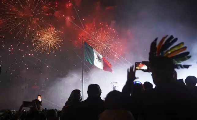 People watch fireworks during the Independence Day celebration at the Zocalo, Mexico City's main square, Monday, Sept. 15, 2025. (AP Photo/Jon Orbach)