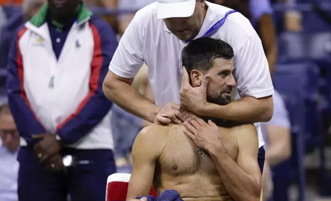 A trainer works on Novak Djokovic, of Serbia, between games against Jan-Lennard Struff, of Germany, during the fourth round of the U.S. Open tennis championships, Sunday, Aug. 31, 2025, in New York. (AP Photo/Andres Kudacki)