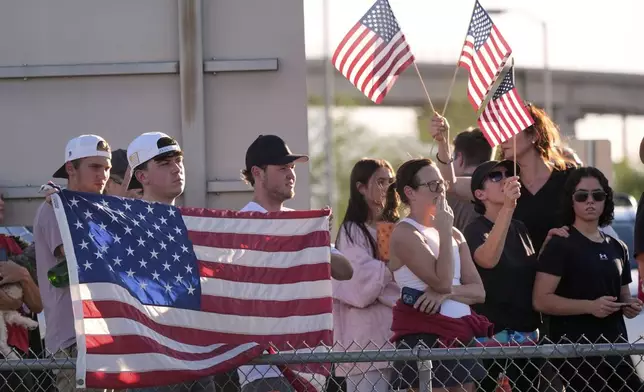 People watch a hearse containing the body of Charlie Kirk, the CEO and co-founder of Turning Point USA, who was shot and killed on Wednesday leave after the body arrived aboard Air Force Two at Phoenix Sky Harbor International Airport, Thursday, Sept. 11, 2025, in Phoenix. (AP Photo/Ross D. Franklin)