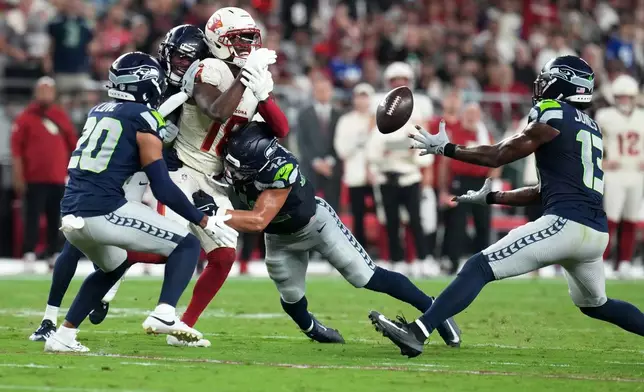 Seattle Seahawks linebacker Ernest Jones IV (13) intercepts a pass intended for Arizona Cardinals wide receiver Marvin Harrison Jr. (18) during the first half of an NFL football game Thursday, Sept. 25, 2025, in Glendale, Ariz. (AP Photo/Rick Scuteri)