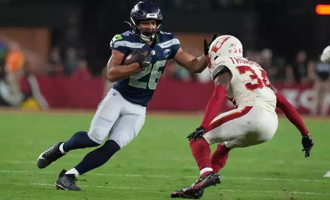 Seattle Seahawks running back Zach Charbonnet (26) runs with the ball as Arizona Cardinals safety Jalen Thompson (34) defends during the first half of an NFL football game Thursday, Sept. 25, 2025, in Glendale, Ariz. (AP Photo/Rick Scuteri)