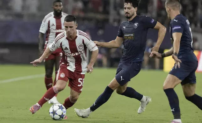 Olympiacos' Daniel Podence fights for the ball against Pafos' Pepe during a Champions League opening phase soccer match between Olympiakos and Pafos at the Georgios Karaiskakis stadium, Piraeus port, near Athens, Greece, Wednesday, Sept. 17, 2025. (AP Photo/Petros Giannakouris)