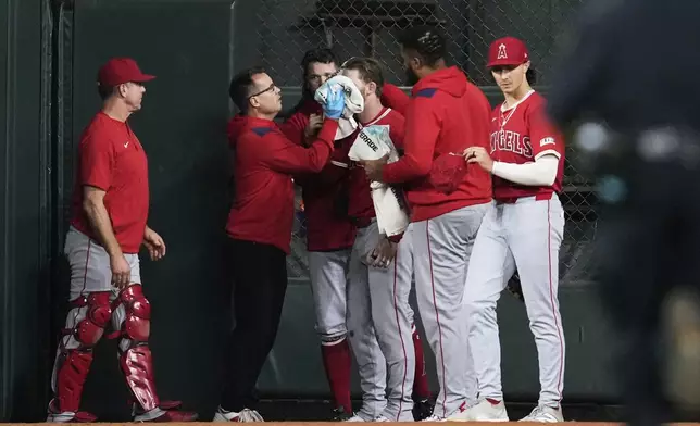 Los Angeles Angels left fielder Taylor Ward, center, is treated for injury during the eighth inning of a baseball game against the Houston Astros in Houston, Sunday, Aug. 31, 2025. (AP Photo/Ashley Landis)
