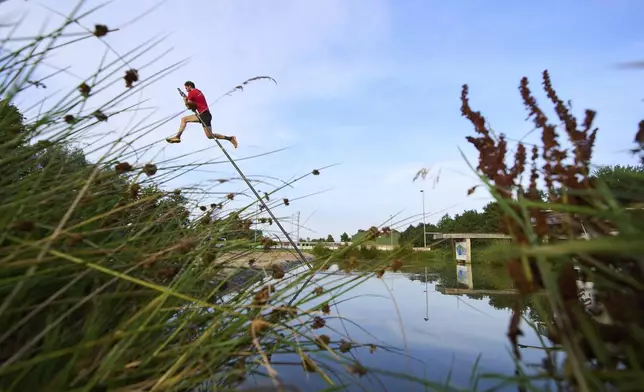 An athlete practices jumping across a body of water during a Fierljeppen competition in Kockengen, Netherlands, Wednesday, Aug. 27, 2025. (AP Photo/Peter Dejong)