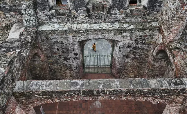 A tourist visits the ruins of Santo Domingo church, built in the 17th century after the city was relocated from its first colonial settlement, which had been destroyed by pirates, in "Casco Viejo," the historic district of Panama City, a UNESCO World Heritage Site, Sunday, Aug. 10, 2025. (AP Photo/Matias Delacroix)