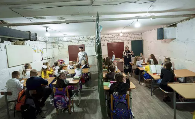 School students listen to their teachers during a lesson, in the basement of a municipal building during the first day in school in Bobryk, Sumy region, Ukraine, Monday, Sept. 1, 2025. The Bobryk school was forced to move to the basement due to endless alarms. (AP Photo/Evgeniy Maloletka)