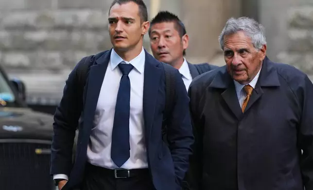 IndyCar champion Alex Palou, left, arrives with his legal team at court at the start of a breach of contract lawsuit with McLaren Racing, in London, Monday, Sept. 29, 2025. (AP Photo/Kirsty Wigglesworth)