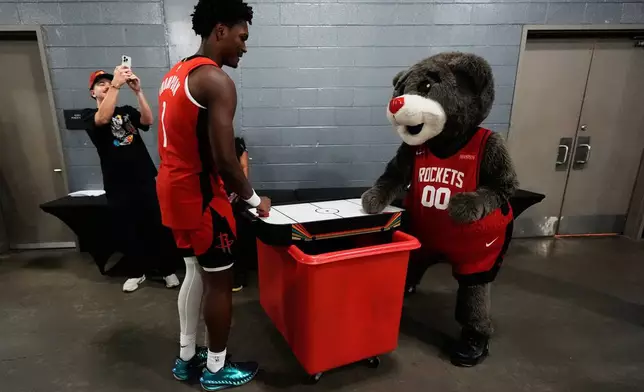 Houston Rockets forward Amen Thompson (1) plays air hockey with mascot Clutch during the NBA basketball team's media day in Houston, Monday, Sept. 29, 2025. (AP Photo/Ashley Landis)