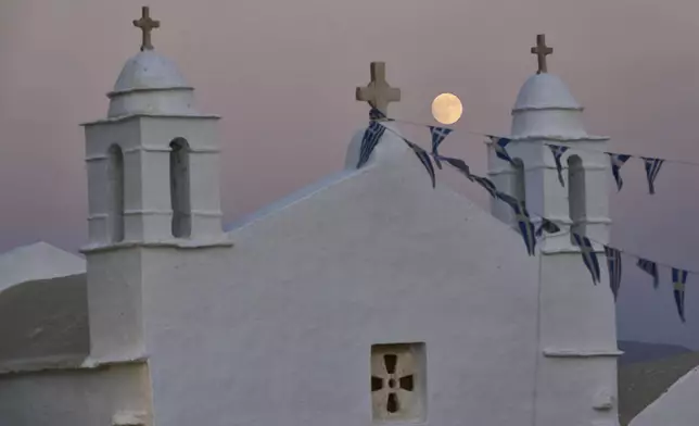 The moon rises behind the family-owned Agios Sostis chapel during its panigiri day on the island of Tinos, Greece, Saturday, Sept. 6, 2025. (AP Photo/Petros Giannakouris)