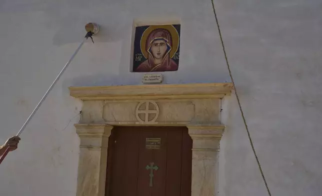 Naim Domi, 50, an Albanian worker who has lived in Greece for 17 years, paints the Panagia Faneromeni co-family-owned chapel, near the village of Pyrgos, on the island of Tinos, Greece, Sunday, Sept. 7, 2025. (AP Photo/Petros Giannakouris)