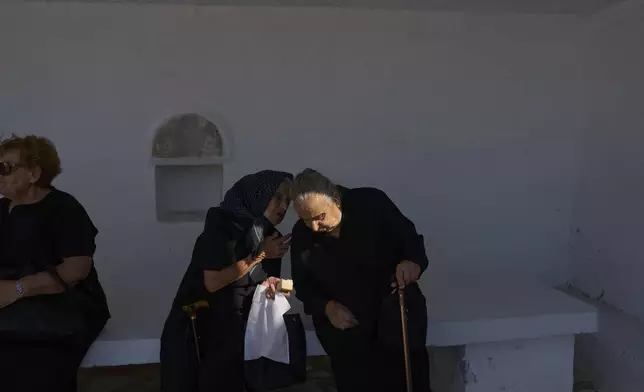 Ioanna Louvari, 96, talks with another elderly woman during a liturgy at the family-owned Agios Sostis chapel on the island of Tinos, Greece, Monday, Sept. 8, 2025. (AP Photo/Petros Giannakouris)