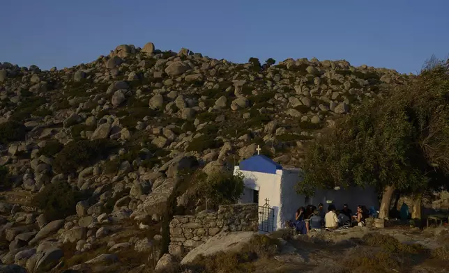 Tourists from the United States enjoy an organized picnic outside Agios Giorgos (St. George), a 200-year-old chapel near the village of Volax on Tinos island, Greece, Friday, Sept. 5, 2025. (AP Photo/Petros Giannakouris)