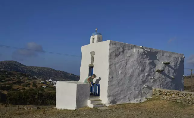Bernadette Foskolos cleans her Agios Athanasios family-owned chapel at the village of Steni, on the island of Tinos, Greece, Saturday, Sept. 6, 2025. (AP Photo/Petros Giannakouris)