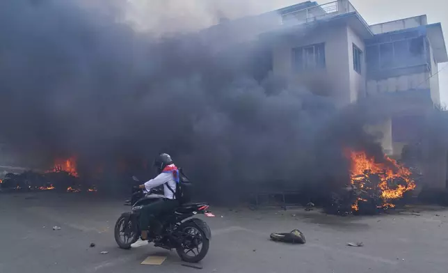 A motorcyclist drives past a burning police station during protests against social media ban and corruption in Kathmandu, Nepal, Tuesday, Sept. 9, 2025. (AP Photo/Niranjan Shrestha)