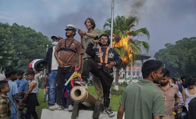 Protesters celebrate at the Singha Durbar, the seat of Nepal's government's various ministries and offices, after burning it down during a protest against a social media ban and corruption in Kathmandu, Nepal, Tuesday, Sept. 9, 2025. (AP Photo/Niranjan Shrestha)
