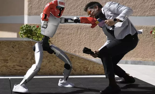 The Unitree G1 robot plays boxing with Aadeel Akhtar CEO and Founder of Psyonic at the first International Humanoid Olympiad at the Olympic Academy, in ancient Olympia, Greece, Monday, Sept. 1, 2025. (AP Photo/Thanassis Stavrakis)