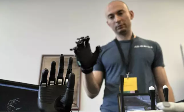 CORRECTS NAME OF COMPANY: Ryan Saavedra, CEO of Alt-Bionics, operates a bionic hand at the first International Humanoid Olympiad at the Olympic Academy, in ancient Olympia, Greece, Monday, Sept. 1, 2025. (AP Photo/Thanassis Stavrakis)