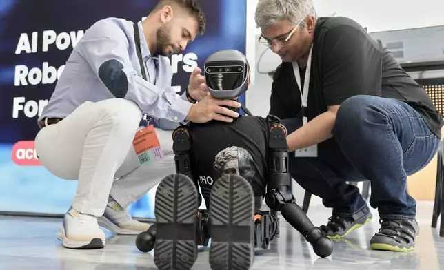 Spiros Makris, right, and Ioannis Karampinas technicians of Acumino replace a battery at the Booster T1 robot during the first International Humanoid Olympiad at the Olympic Academy, in ancient Olympia, Greece, Monday, Sept. 1, 2025. (AP Photo/Thanassis Stavrakis)