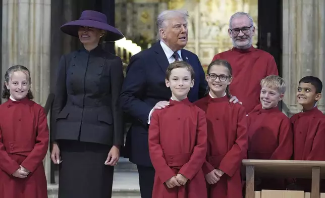 President Donald Trump and first lady Melania Trump pose with a childrens choir as they receive a tour of St. George's Chapel at Windsor Castle, Windsor, England, Wednesday, Sept. 17, 2025. (AP Photo/Evan Vucci, Pool)