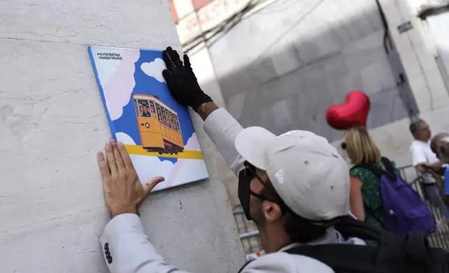 A person that wished to remain anonymous, places a painting showing a funicular with one driver and fifteen passengers, by the downtown stop of the Gloria funicular, a tourist streetcar that derailed and crashed, in Lisbon, Saturday, Sept. 6, 2025. (AP Photo/Armando Franca)