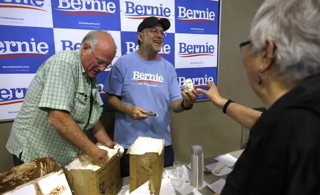 FILE - Ben &amp; Jerry's co-founder Ben Cohen, left, and fellow co-founder Jerry Greenfield, center, scoop ice cream before a campaign event for Sen. Bernie Sanders, I-Vt., not shown, Sept. 1, 2019, in Raymond, N.H. (AP Photo/Steven Senne, File)