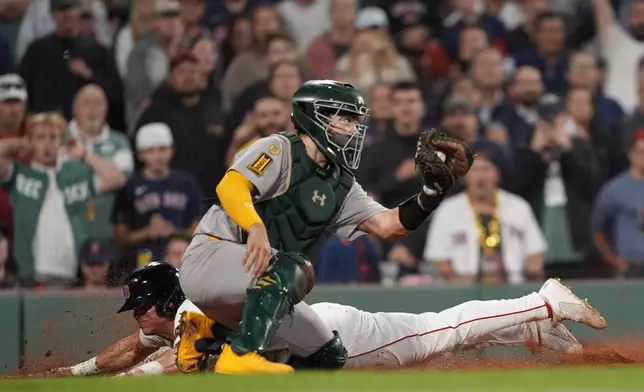 Boston Red Sox Nate Eaton, back, dives home for the winning run in the 10th inning past Athletics catcher Shea Langeliers in a baseball game, Wednesday, Sept. 17, 2025, in Boston. (AP Photo/Robert F. Bukaty)