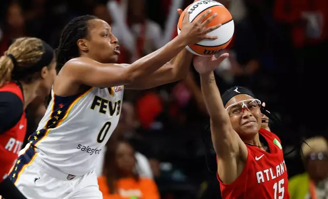 Indiana Fever guard Kelsey Mitchell (0) and Atlanta Dream guard Allisha Gray (15) reach for a loose ball during the first half of Game 3 in the first round of the WNBA basketball playoffs, Thursday, Sept. 18, 2025, in Atlanta. (AP Photo/Butch Dill)