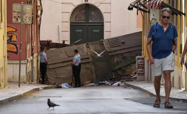 Police officers cordon off the area where a tourist streetcar derailed and crashed in Lisbon, Portugal, Thursday, Sept. 4, 2025. (AP Photo/Armando Franca)
