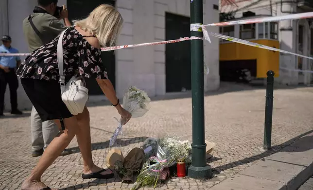 A woman places flowers at the site where a tourist streetcar derailed and crashed in Lisbon, Portugal, Thursday, Sept. 4, 2025. (AP Photo/Armando Franca)