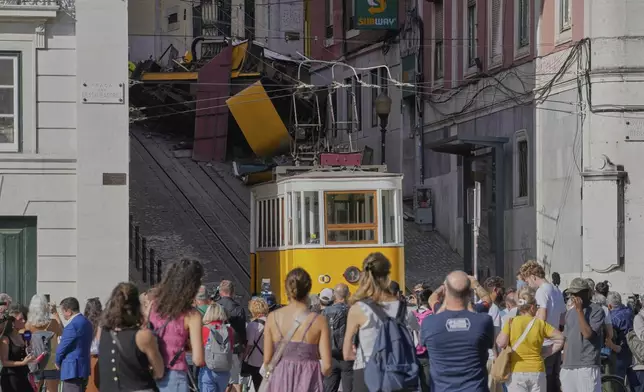 People look at a tourist streetcar that derailed and crashed in Lisbon, Portugal, Thursday, Sept. 4, 2025. (AP Photo/Armando Franca)