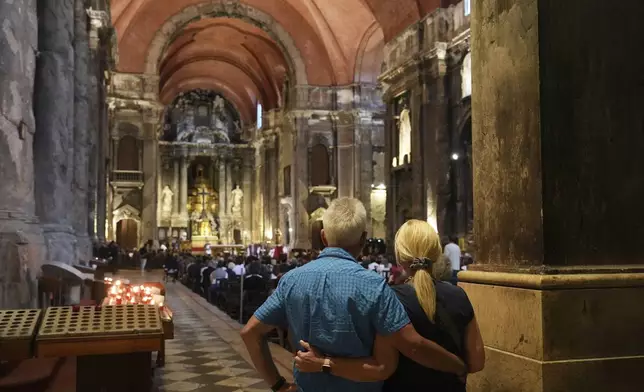 A couple attend a mass for the victims of a tourist streetcar that derailed and crashed in Lisbon, at the Church of St. Dominic, Thursday, Sept. 4, 2025. (AP Photo/Ana Brigida)