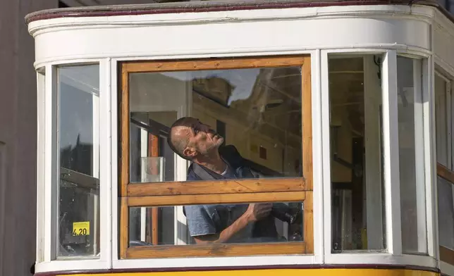 A police officer inspects a wagon at the site where a tourist streetcar derailed and crashed in Lisbon, Portugal, Thursday, Sept. 4, 2025. (AP Photo/Armando Franca)