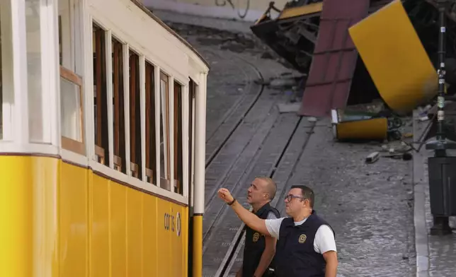 Police officers inspect the site where a tourist streetcar derailed and crashed in Lisbon, Portugal, Thursday, Sept. 4, 2025. (AP Photo/Armando Franca)