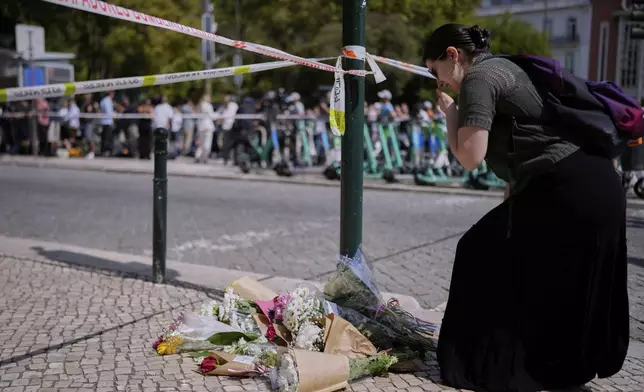 A woman reacts as she places flowers at the site where a tourist streetcar derailed and crashed in Lisbon, Portugal, Thursday, Sept. 4, 2025. (AP Photo/Armando Franca)