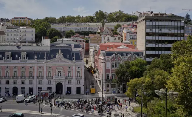 People look at a tourist streetcar derailed and crashed in Lisbon, Portugal, Thursday, Sept. 4, 2025. (AP Photo/Armando Franca)