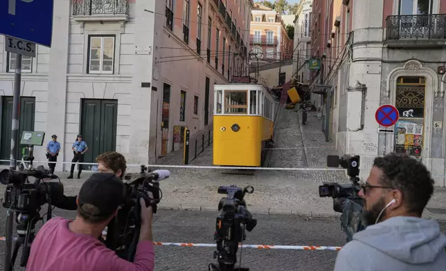 TV cameras record the site where a tourist streetcar derailed and crashed in Lisbon, Portugal, Thursday, Sept. 4, 2025. (AP Photo/Armando Franca)
