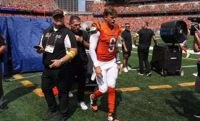 Cincinnati Bengals quarterback Joe Burrow, center, is exits the medical tent for the locker room after suffering an injury during the second quarter of an NFL football game against the Jacksonville Jaguars, Sunday, Sept. 14, 2025, in Cincinnati. (AP Photo/Kareem Elgazzar)