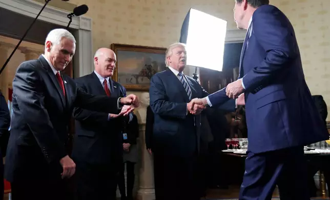 FILE - Vice President Mike Pence, left, and Secret Service Director Joseph Clancy stand as President Donald Trump shakes hands with FBI Director James Comey during a reception for inaugural law enforcement officers and first responders in the Blue Room of the White House, Jan. 22, 2017 in Washington. (AP Photo/Alex Brandon, File)