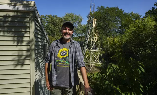Alex Babich, pose in front of the structure that surrounds his nearly 36-feet high sunflower that holds the world record for the tallest flower at his home in Fort Wayne, Ind., Thursday, Sept. 11, 2025. (AP Photo/Michael Conroy)