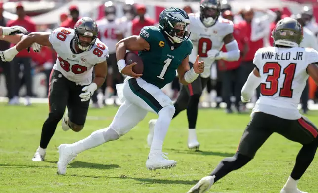 Philadelphia Eagles quarterback Jalen Hurts (1) rushes past Tampa Bay Buccaneers defensive line Logan Hall (90) during the second half of an NFL football game Sunday, Sept. 28, 2025, in Tampa, Fla. (AP Photo/Chris O'Meara)