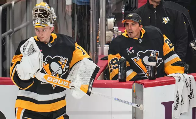 Pittsburgh Penguins goaltender Sergei Murashov, left, skates back to his goal after a timeout visiting with fellow goalie Marc-Andre Fleury during the first period of an pre-season NHL hockey game against the Columbus Blue Jackets in Pittsburgh, Saturday, Sept. 27, 2025. (AP Photo/Gene J. Puskar)