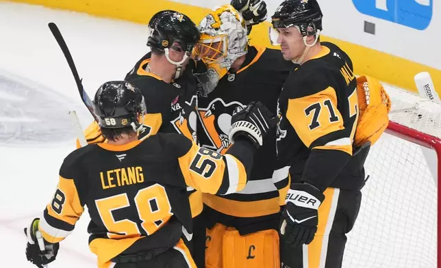 Pittsburgh Penguins goalie Marc-Andre Fleury, center, is surrounded by Kris Letang (58), Sidney Crosby, second from left, and Evgeni Malkin (71) following a pre-season NHL hockey game against the Columbus Blue Jackets in Pittsburgh, Saturday, Sept. 27, 2025. (AP Photo/Gene J. Puskar)