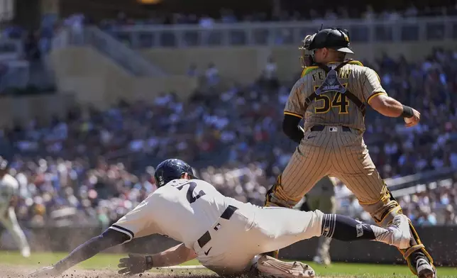 Minnesota Twins' Brooks Lee (2) slides past San Diego Padres catcher Freddy Fermin (54) to score off a sacrifice fly hit by Minnesota Twins' Ryan Jeffers (27) during the fifth inning of a baseball game Sunday, Aug. 31, 2025, in Minneapolis. (AP Photo/Abbie Parr)