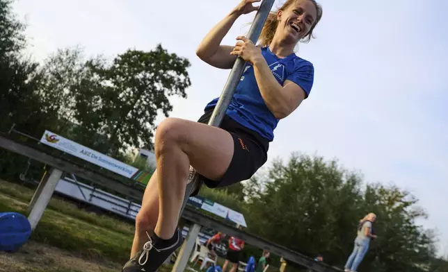 An athlete practices the climbing part of the jump prior to crossing a body of water with a carbon pole during a Fierljeppen competition in Kockengen, Netherlands, Wednesday, Aug. 27, 2025. (AP Photo/Peter Dejong)