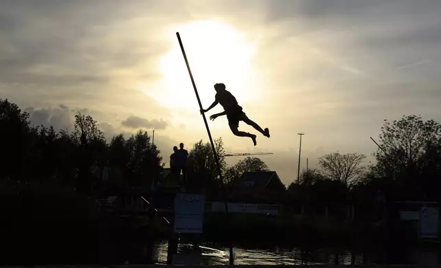 An athlete jumps across a body of water with a long carbon pole during a Fierljeppen competition in Kockengen, Netherlands, Wednesday, Aug. 27, 2025. (AP Photo/Peter Dejong)
