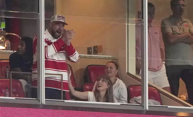 Taylor Swift sits with fiance Travis Kelce as they watch during the second half of an NCAA college football game between Cincinnati and Nebraska Thursday, Aug. 28, 2025, at Arrowhead Stadium in Kansas City, Mo. (AP Photo/Charlie Riedel)