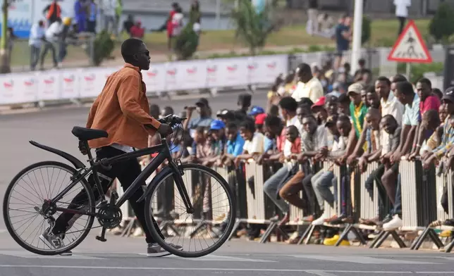 A man pushes his bicycle as he crosses the road during the team time trial mixed relay event, at the road cycling World Championships in Kigali, Rwanda, Wednesday, Sept. 24, 2025. (AP Photo/Jerome Delay)