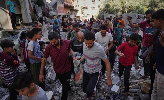 Palestinians carry the body of Hassan Nasr, 12, from the rubble of his relatives home, which was hit by an Israeli military strike in Zawaida, central Gaza Strip, Thursday, Sept. 25, 2025. (AP Photo/Abdel Kareem Hana)
