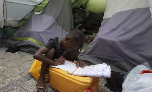 A child does her homework at a church-turned-shelter for people displaced by gang violence in Port-au-Prince, Haiti, Wednesday, Sept. 17, 2025. (AP Photo/Odelyn Joseph)